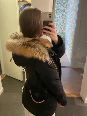 Parkajacka med äkta päls från Parajumpers - Säljer en svart parkajacka (Doris) från Parajumpers med äkta päls runt huvan och snygga gula detaljer. Jackan har både dragkedja och knappar framtill, flera fickor och en varm, robust känsla. (Den är i storlek M men jag brukar ha S, för jämförelse)💗💗