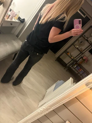 Svarta bootcut jeans från Denim Rebel - Säljer ett par svarta jeans från Denim Rebel i storlek 34. Modellen har bootcut-ben och klassisk femficksdesign. Jeansen är i ett mjukt denim-material med en mörk tvätt och sitter snyggt över höfterna. Perfekt för dig som gillar en lite retro vibe.