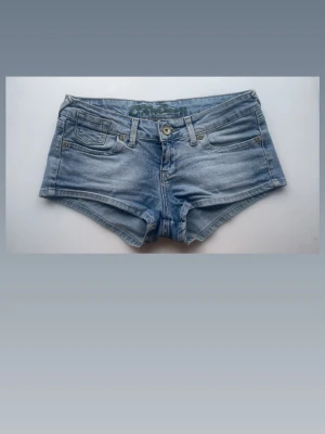 Lågmidjade jeansshorts  - Säljer dessa ljusblå lågmidjade jeansshortsen med klassisk femficksdesign och grönt broderi på bakfickorna💗                                               Midjemått: 38cm tvärs över                           Grenhöjd: 19cm                                                Skriv om ni har några frågor💞❣️