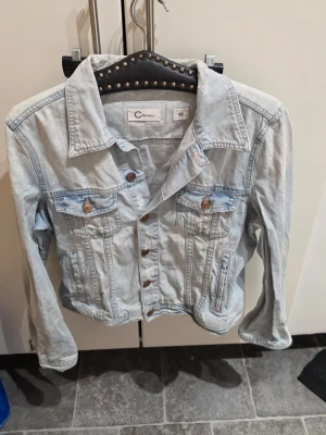 Ljusblå jeansjacka från Cubus  - Snygg ljusblå jeansjacka från Cubus i 100% bomull. Klassisk modell med krage, bröstfickor med knappar och knappstängning framtill. Perfekt att slänga på över en hoodie eller t-shirt för en chill look.