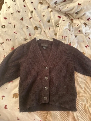 Svart stickad kofta från Monki - Mysig svart stickad kofta från Monki i storlek XS. Koftan har v-ringning, ribbade kanter och fem knappar framtill. Perfekt för lager på lager och chill höst- och vinterdagar.