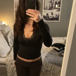 Svart långärmad topp med spets H&M - Säljer en svart långärmad topp från H&M med djup v-ringning och snygga spetsdetaljer vid urringningen. Modellen är croppad och sitter tight. Det är en body som är omsydd till en vanlig tröja💕