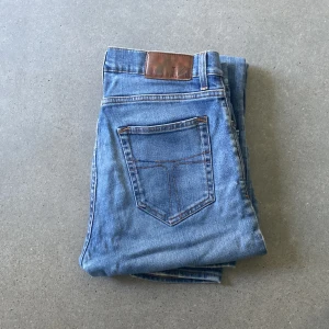 Tiger of Sweden jeans - Säljer ett par Tiger of Sweden Pistelero jeans i ljusblå tvätt med klassisk femficksdesign och snygga slitningar. Jeansen har raka ben och normal passform, tillverkade i mjukt jeanstyg. Perfekta för dig som gillar en avslappnad men stilren look.