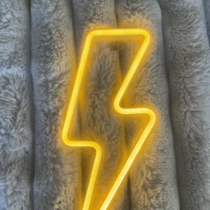 USB Neon LED Blixtlampa - Dekorativ neonlampa i form av en blixt, drivs via USB. Ger ett starkt gult sken och passar perfekt som väggdekoration. Lampan är i gott skick utan synliga defekter eller slitage. Enkel att använda och koppla in.