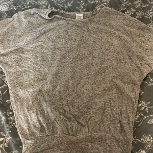 Gråmelerad tröja från Stories S - En gråmelerad tröja från Stories i storlek S. Tröjan har en avslappnad passform med bred mudd nedtill och rund halsringning. Perfekt för dig som gillar en enkel och stilren look. Materialet är mjukt och känns skönt mot huden.