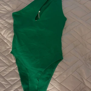  Body, one shoulder - Snygg grön body från Zara i one shoulder-modell med en cool cut-out detalj framtill. Materialet är mjukt och stretchigt. Perfekt till dig som vill ha en body som är både basic och coolt!