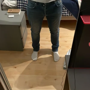  jeans från Morris, slim fit - Säljer ett par snygga blå jeans från Morris med klassisk femficksdesign och diskreta slitningar. Jeansen har slim passform. Storleks taggen är tyvärr bortklippta från tidigare ägaren men skulle säga att den passar 32/33