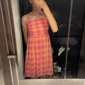 Rosa och gul rutig sommarklänning Linex - Superfin klänning från Linex i rosa och gult rutigt mönster. Klänningen har smala axelband, rynkad överdel och lätt utställd kjol. Materialet är mjukt och känns skönt mot huden. Nypris är 399 