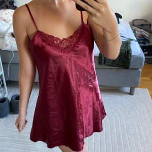 Vinröd satin klänning med spets - Jag är 172cm och bär vanligtvis S/36 Kolla gärna in mina andra annonser och få rabatt på bundles🌸♻️Säljer en vinröd kortklänning i satin med tunna axelband och vacker spetsdetalj vid v-ringad hals. Klänningen har en lätt A-linjeformad siluett och känns både mjuk och glansig mot huden. Perfekt för dig som gillar en feminin och elegant look.