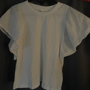 Vit blus med volangärm från Kappahl - Supersöt vit blus från Kappahl med breda volangärmar. Perfekt för dig som gillar en luftig och stilren look. Jättefin men säljs för att den inte kommer till användning. Kontakta för egna bilder.