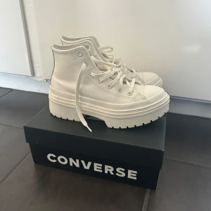 Vita Converse sneakers med platåsula - Säljer ett par vita Converse sneakers i skinn med chunky platåsula och snörning. Klassisk hög modell med rund tå och grov yttersula för extra attityd. Perfekta för dig som vill sticka ut med en clean och modern look. Storlek EUR 37. Nypris 1299 kr. Bara använda ett fåtal gånger, originalkartongen finns kvar.