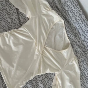 Krämvit omlottopp med utsvängda armar - Säljer en krämvit omlottopp med v-ringning och puffiga ärmar. Toppen har lätt tyg och rynkade detaljer i sidorna som ger en snygg form. Perfekt för dig som gillar romantisk och trendig stil.