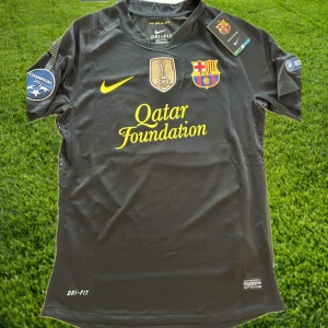 Messi - Barcelona retro tröja från 11/12  - Nyskick/helt oanvänd Barcelona Messi tröja från säsongen 2011/2012. Tröjan har även Champions League trycken på ärmarna. Storleken är M men skulle säga att den sitter mer som S. Tveka inte att höra av er för fler frågor och bilder!