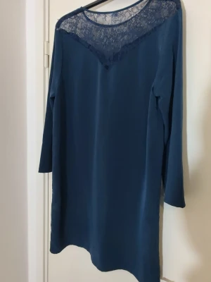 Snygg Marinblå klänning med spets i NySkick  - Festlig kortklänning med långärmar och spets på fram och baksidan. Oanvänd                                                                I strlk 40