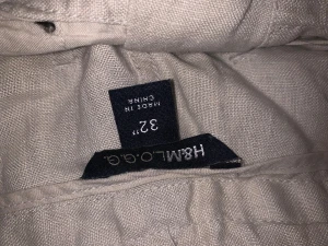 Beige linnebyxor från H&M LOGG - Säljer ett par beige linnebyxor från H&M LOGG i storlek 32. Byxorna har avslappnad passform, snörning i midjan och raka ben med dragsko längst ner. Perfekta för chill dagar och sommarhäng. Materialet är linne som ger en skön och luftig känsla.