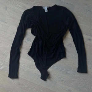 Svart långärmad body - Säljer en svart långärmad body med rund halsringning. Tight passform och klassisk design som passar till många olika outfits. Perfekt att styla med jeans eller kjol för en trendig look.