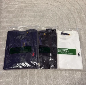 Polo Ralph Lauren t-shirt 3 pack vit svart och navy slim fit - Snygga t-shirts från Polo Ralph Lauren i navyblått och vitt och svart . Klassisk design med kort ärm och rund hals, ikoniska Polo-loggan broderad på bröstet i rött eller vitt. Mjukt bomullsmaterial som känns skönt mot huden. Perfekt för dig som gillar stilrena och tidlösa plagg. Slim fit så sitter som M