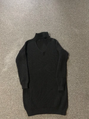 Svart stickad poloklänning - Svart stickad klänning med polokrage och v-ringning. Modellen är långärmad och har en ribbad struktur som ger en cool och mysig känsla. Perfekt för dig som gillar enkel men snygg stil med lite edge.