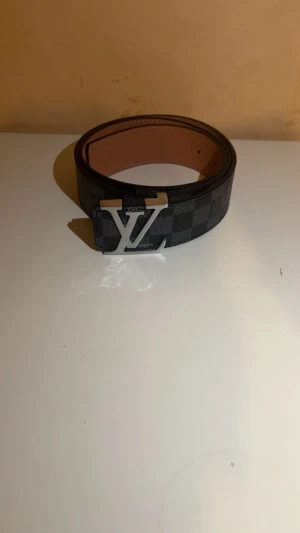 Svart randigt bälte 110 cm - Ett svart randigt bälte med ett silver spänne helt nytt och mycket bra kvalité.