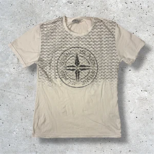 Stone Island T-Shirt - Säljer denna vita Stone Island T-Shirten med svart tryck. Tröjan kommer i stl S och är i mycket bra skick. Hör av er vid frågor, pris kan diskuteras vid snabb affär!