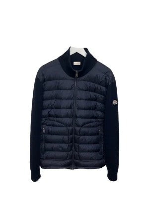 Mörkblå Moncler cardigan i storlek L - Snygg mörkblå cardigan från Moncler med quiltad front och ärmar i stickad ullmix. Jackan har hög krage, dragkedja framtill och två fickor med dragkedja. Klassisk Moncler-logga på ena ärmen. Perfekt för dig som vill ha en stilren och exklusiv look. På sista bilden ser du allt noggrant, en liten söm som har gått upp så därför går priset neråt✅
