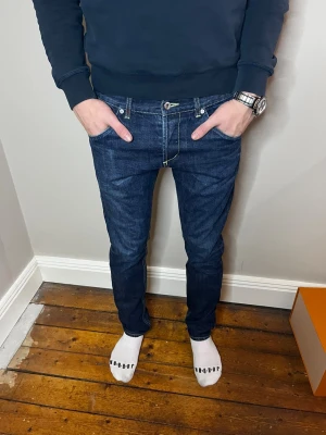 Dondup Jeans - Säljer ett par mörkblå jeans från Dondup med snygga kontrastsömmar och unika bakfickor med dragkedjedetaljer. Klassisk femficksmodell med låg midja och raka ben. Märkespatch baktill i linningen. Storlek 32 passar som W30 L32. Pris är diskuterbart vid snabb affär.