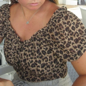 Leopardmönstrad blus med puffärm - Säljer en croppad blus med leopardmönste. Blusen har puffiga korta ärmar och knappar framtill (kan ha off-shoulder). Materialet är lätt och luftigt.