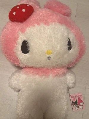 My melody kawaii mjukis djur -   en stor My Melody-mjukis med rosa och vit päls,  en röd jordgubbe på huvudet. 