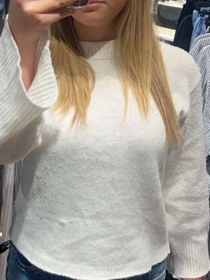 Vit stickad tröja med ribbade ärmar - Säljer en vit stickad tröja med långärmade och ribbade muddar. Tröjan har en enkel och clean design med rund hals och mjukt material som känns skönt mot huden. Den är tunnare än en vanlig stickad. Perfekt för varma kvällar när man inte vill ha nägot för tjockt