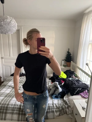Svart t-shirt från KappAhl - Enkel svart t-shirt från KappAhl i storlek S. Modellen är klassisk med rund hals och korta ärmar. T-shirten är i mjuk bomull och har en normal passform som funkar till allt. Perfekt basplagg för garderoben.