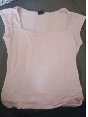 Ljusrosa ärmlös topp med fyrkantig hals - Säljer en ljusrosa topp med fyrkantig halsringning och ärmlös design. Toppen har en enkel och stilren look, perfekt för varma dagar. Materialet känns mjukt och lätt mot huden, och färgen är diskret men ändå söt.