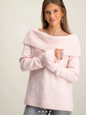 Ljusrosa offshoulder stickad tröja - Supermjuk och fluffig ljusrosa stickad tröja med bred offshoulder-krage. Tröjan har långa ärmar och ribbade detaljer vid krage, ärmslut och nederkant. Perfekt för dig som gillar en chill och söt stil.