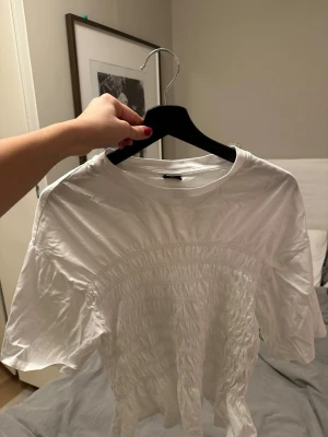 Vit t-shirt med smockdetaljer - Säljer en vit t-shirt med coola smockdetaljer , storlek L, men mindre i storleken, passar mig som är S