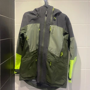 Mörkgrön skidjacka från Tenson - Skalskidjacka från Tenson i olika färger, storlek S✅ det är en softshell jacka med flera dragkedjor och andra funktioner såsom RECCO. Perfekt för dig som vill ha en snygg och funktionell jacka till utelivet. Nypris 4000.