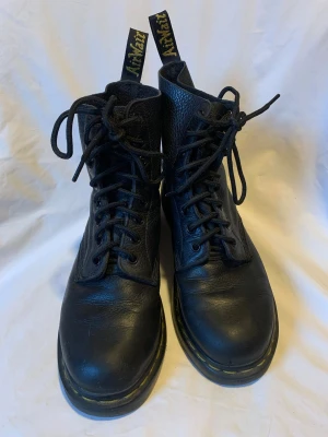 Svarta Dr. Martens boots i skinn - Säljer ett par klassiska svarta Dr. Martens boots i modellen Pascal i mjukt smidigt finkornigt Virginia-läder. Använda men väl omskötta och mycket fräscha. Skosnörena är utbytta och nya. Kan skicka eller mötas upp i Stockholm (Södermalm). 