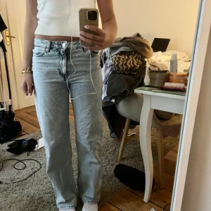 Ljusblå raka jeans - Säljer ett par ljusblå jeans med rak passform och klassisk femficksdesign. Jeansen har normalhög midja och stängs med dragkedja och knapp. Perfekta till vardags för en avslappnad stil.