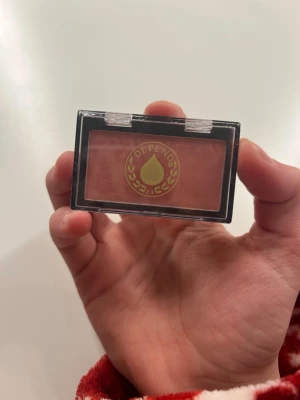 Depend rouge i persikoton - Rouge från Depend i en snygg persikoton som ger fräsch färg till kinderna. Kommer i en kompakt plastförpackning med genomskinligt lock och Depend-logga. Perfekt storlek för att ha med i väskan. Innehåller 2,88 g puder.