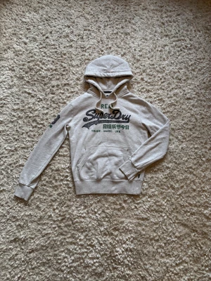 Grå hoodie från superdry - Snygg o eftertraktad hoodie från superdry. Använd men i gott skick! Storlek S.