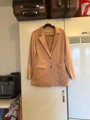 Mönstrad kavaj från Cream, storlek M - Säljer en snygg kavaj från Cream i storlek M. Jackan har ett färgglatt zickzackmönster i rosa, beige och grönt, klassisk krage och två knappar framtill. Den har två fickor med lock och är långärmad. Perfekt för dig som vill sticka ut lite extra! Mycket fint skick, jag hittar inga synliga anmärkningar eller defekter. 