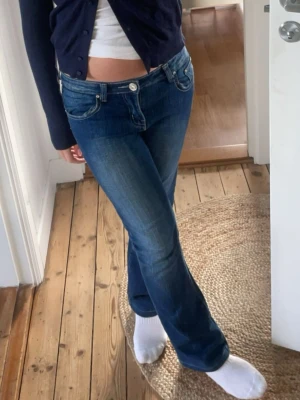 Blå super lågmidjade urtvättade  bootcut jeans vintage  - Snygga blå jeans från Huohu med bootcut-snitt och låg midja. Jeansen har klassisk femficksdesign, guldfärgad knapp med glittrig detalj och slitningar på låren för en cool look. Materialet är jeans och passformen är lågmidjade och de är lite som weekday jeansen med urtvättningen