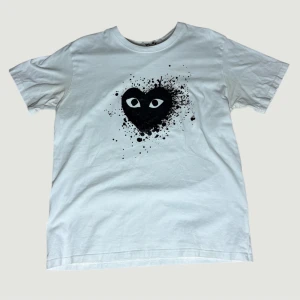 Unik CDG T-shirt  - Säljer en unik och sällsynt vit t-shirt från Comme des Garçons PLAY med ett stort svart hjärta och ögon på bröstet, omgivet av coola färgstänk. T-shirten har rund hals. Tröjan är i Storlek L men passar lite mindre! Bara att höra av er vid frågor, priset är diskuterbart vid snabb affär!