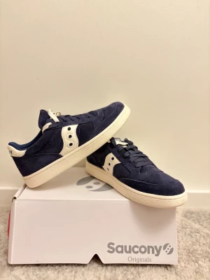 Saucony Originals mörkblå sneakers - Saucony Originals sneakers i mörkblå mocka med vita detaljer och logga på sidan och hälen.  Storlek 40,5. Säljer dessa pga för små. Aldrig använt dessa utan provat en gång. Pris kan diskuteras vid snabb affär. Passar perfekt för all-around kläder.