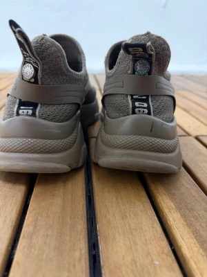 Steve Madden beige sneakers - Säljer ett par snygga beige sneakers från Steve Madden med stickad ovandel och grov platt sula. Skorna har snörning och coola detaljer med text på hälen. Perfekt för dig som gillar streetstyle och vill ha något bekvämt och trendigt.