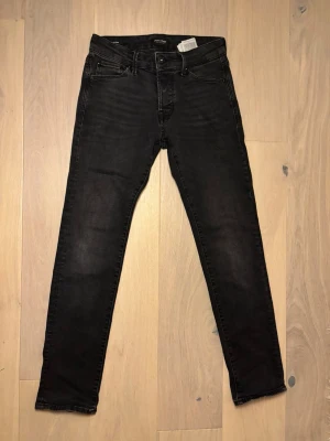 Svarta jeans från Jack & Jones - Ett par riktigt schysta svart jeans från Jack & Jones i jättebra skick. Dem är i använt skick men har inga defekter. Jeansen är Slim-Fit och är i storleken W28/L30. Pris kan diskuteras! 