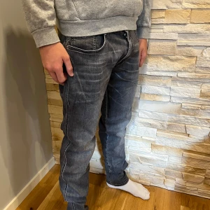 Replay Anbass svarta slim jeans 34 - Säljer ett par Replay Anbass jeans i svart tvätt med snygga slitningar. Modellen är slim fit med klassisk femficksdesign och dragkedjegylf. Jeansen har en mörkgrå ton och är tillverkade i mjukt denimtyg som sitter skönt hela dagen. W34/L29