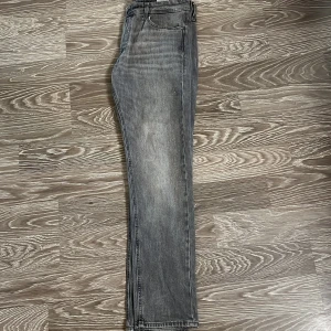 Grå jeans från Jack & Jones, 30/32 - Säljer ett par grå jeans från Jack & Jones i storlek 30/32. Jeansen har klassisk femficksdesign, raka ben och snyggt tvättad finish. Perfekta för dig som gillar en stilren och enkel look. Materialet är slitstarkt denim i bomull.