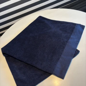 Mörkblå halsduk från Hemtex - Snygg och enkel mörkblå halsduk från Kid Hemtex i mjuk bomull. Halsduken har en klassisk rektangulär form och är helt enfärgad utan mönster. Perfekt att slänga över axlarna för en chill look. 180 x 90cm