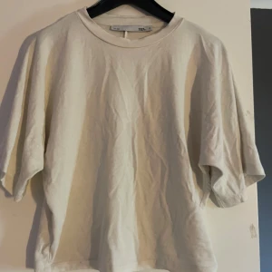 Beige t-shirt från 157, storlek S - En enkel och clean beige t-shirt från 157 i storlek S. T-shirten har korta ärmar, rund hals och är gjord i mjuk bomull. Passformen är loose och den neutrala färgen gör den lätt att matcha med allt. Perfekt för dig som gillar minimalistisk stil.