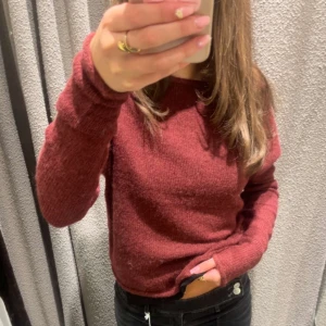 Vinröd stickad offshoulder-tröja - Säljer en vinröd stickad tröja med offshoulder-design och långa ärmar. Tröjan har en mjuk och skön känsla, perfekt för kyligare dagar. Enkel och stilren modell som är lätt att matcha med olika outfits.