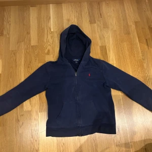 Ralph lauren zip hoddie - En snygg ralph lauren zip hoodie i L barnstorlek skulle säga att den passar runt 160-170 cm. Höjd 55cm och Bred 46cm  Tröjan är lite urtvättad men annars inget fel. Priset kan diskuteras vid snabb affär